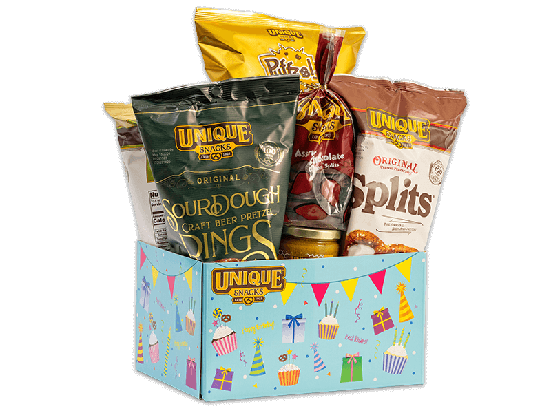Happy Birthday light blue basket box with different colored present boxes party hats, and cupcakes all over it with the unique snacks logo in the upper left hand corner, filled with various Unique Snacks products