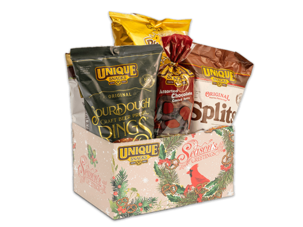 Cardinal basket box that has a wreath, red bird, and seasons greetings written in cursive on it, filled with various Unique Snacks products