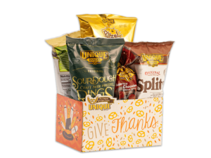 Thanksgiving basket box, pilgrim hat with turkey feathers and text, "Give Thanks" on box filled with various Unique Snacks products