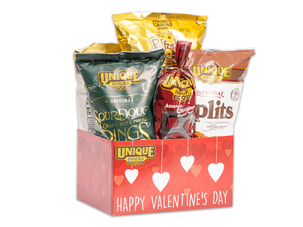 Valentine basket box with red hearts, hanging white hearts, and Valentine’s Day written in white on it, filled with various Unique Snacks products